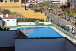 Une piscine à l’eau d’un bleu limpide, entourée d’un mur blanc et d’une pelouse verdoyante.