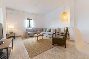 A modern living room with a sofa, armchair, coffee table, and a television.