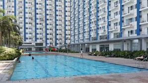 A swimming pool surrounded by a multi-story residential building with balconies. - Cool Place Light Residences (Mandaluyong)