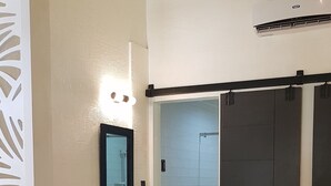 A modern hotel room with a bed, a wardrobe, and a shower area. - Cool Place Light Residences (Mandaluyong)