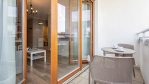 A modern apartment with a balcony, sliding glass doors, a dining area, and a kitchen.