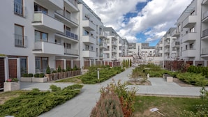 A modern apartment complex with multiple balconies, a central pathway, and landscaped areas.