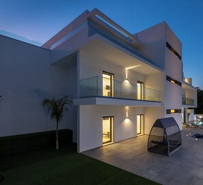 Un immeuble moderne à plusieurs étages, doté de balcons, d’un espace extérieur aménagé et couvert, et d’une piscine.
