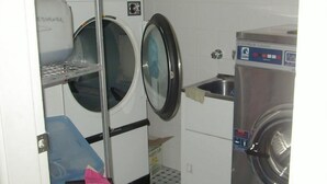 A laundry room with two washing machines, a drying rack, and a sink. - Sinclairs City Hostel (Surry Hills)