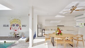 A modern kitchen with white cabinets, a wooden dining table, and a ceiling fan. - Villa Kirana (Seminyak)