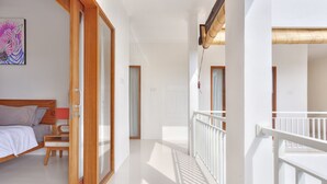 A bedroom with a bed, a desk, and a chair. There is a balcony with a railing. - Villa Kirana (Seminyak)