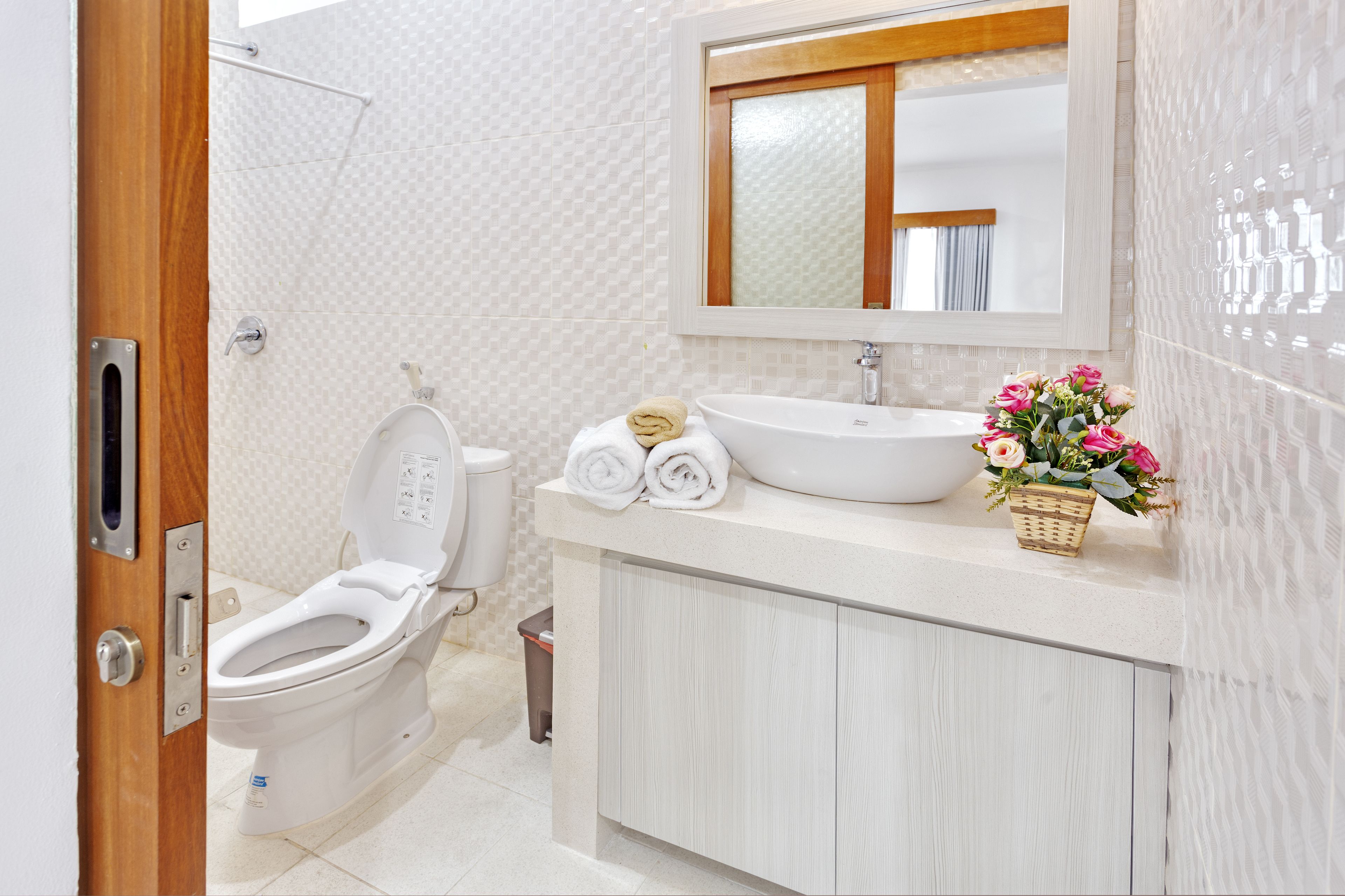 A modern bathroom with a toilet, sink, and mirror.