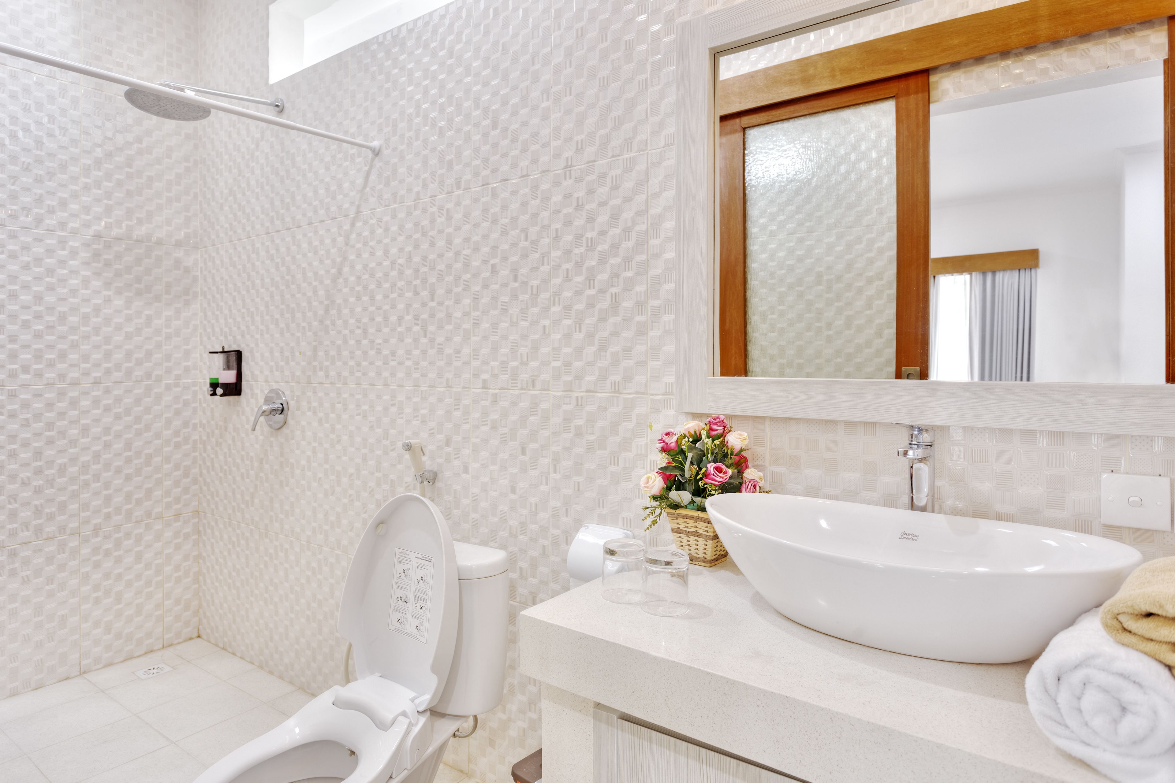 Un baño moderno con inodoro blanco, un lavamanos grande y una zona de ducha.