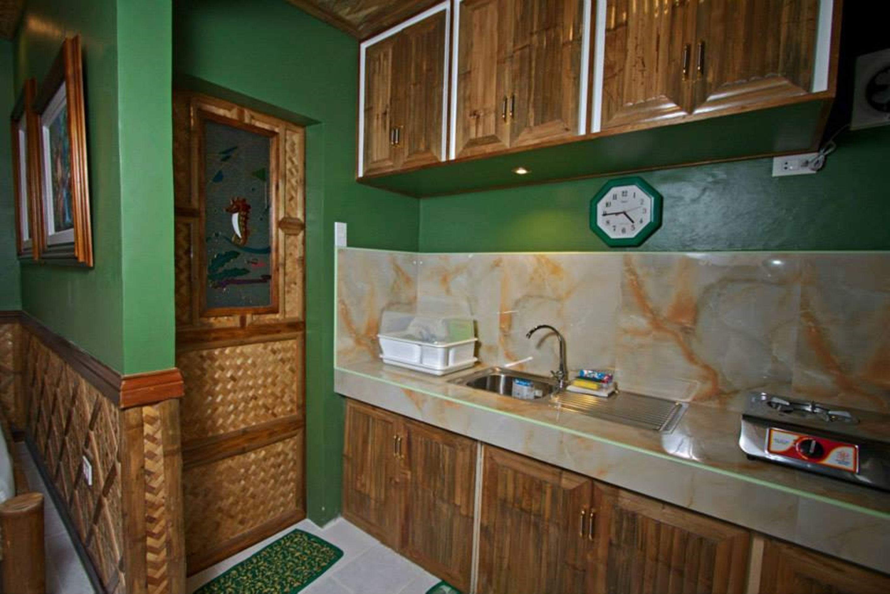 Una cocina con armarios de madera, encimera de mármol y un reloj en la pared.