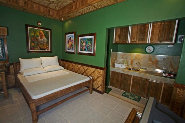 A room with a bed, a sink, and wooden cabinets.