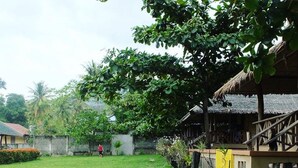 A pathway leading to a building with a thatched roof, surrounded by lush greenery and a well-maintained lawn. - Villa Anastacia White Beach Puerto Galera (Puerto Galera)