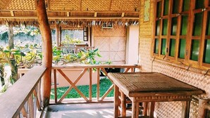 A wooden deck with a table and benches, surrounded by a thatched roof and glass windows. - Villa Anastacia White Beach Puerto Galera (Puerto Galera)