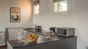 Une cuisine équipée d’un panier de fruits, d’une machine à café, d’un four à micro-ondes et d’une bouilloire.
