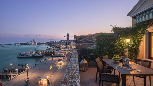 Une terrasse offrant une vue sur l’eau et le paysage urbain, avec notamment un bateau et une église.
