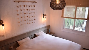 A bedroom with a bed, a wall-mounted light fixture, a window with a view, and a decorative wall piece. - House for 6 persons with private pool and large garden in L'Escala (L'Escala)