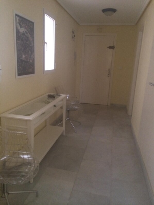 A narrow hallway with a white sink, a chair, and a door at the end. - 3 bedrooms and 2 full bathrooms, very comfortable and well equipped. (Denia)