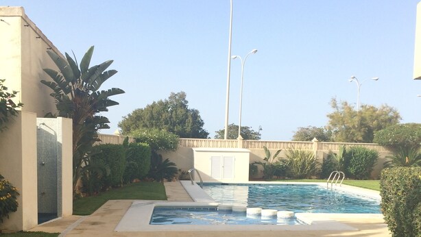 A swimming pool with a small waterfall feature, surrounded by a well-maintained lawn and various plants. - 3 bedrooms and 2 full bathrooms, very comfortable and well equipped. (Denia)