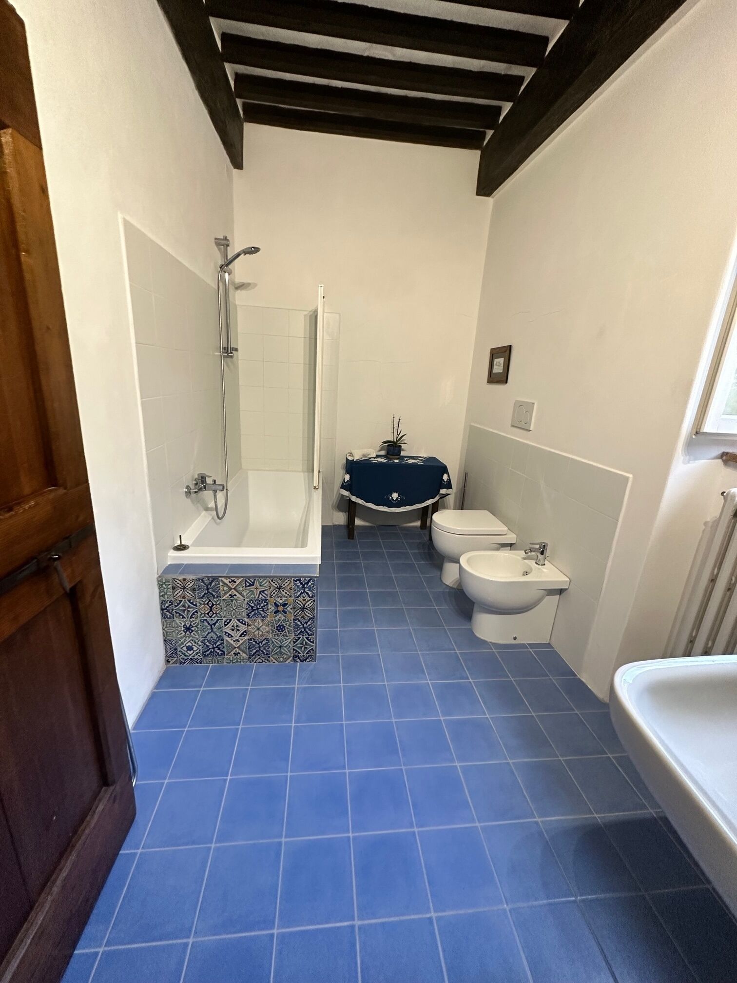 A bathroom with a bathtub, two toilets, a bidet, and a sink.