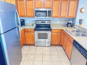 A kitchen with wooden cabinets, a stainless steel refrigerator, a microwave, an oven, and a dishwasher.