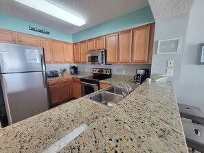 A kitchen with granite countertops, wooden cabinets, stainless steel appliances, and a microwave.
