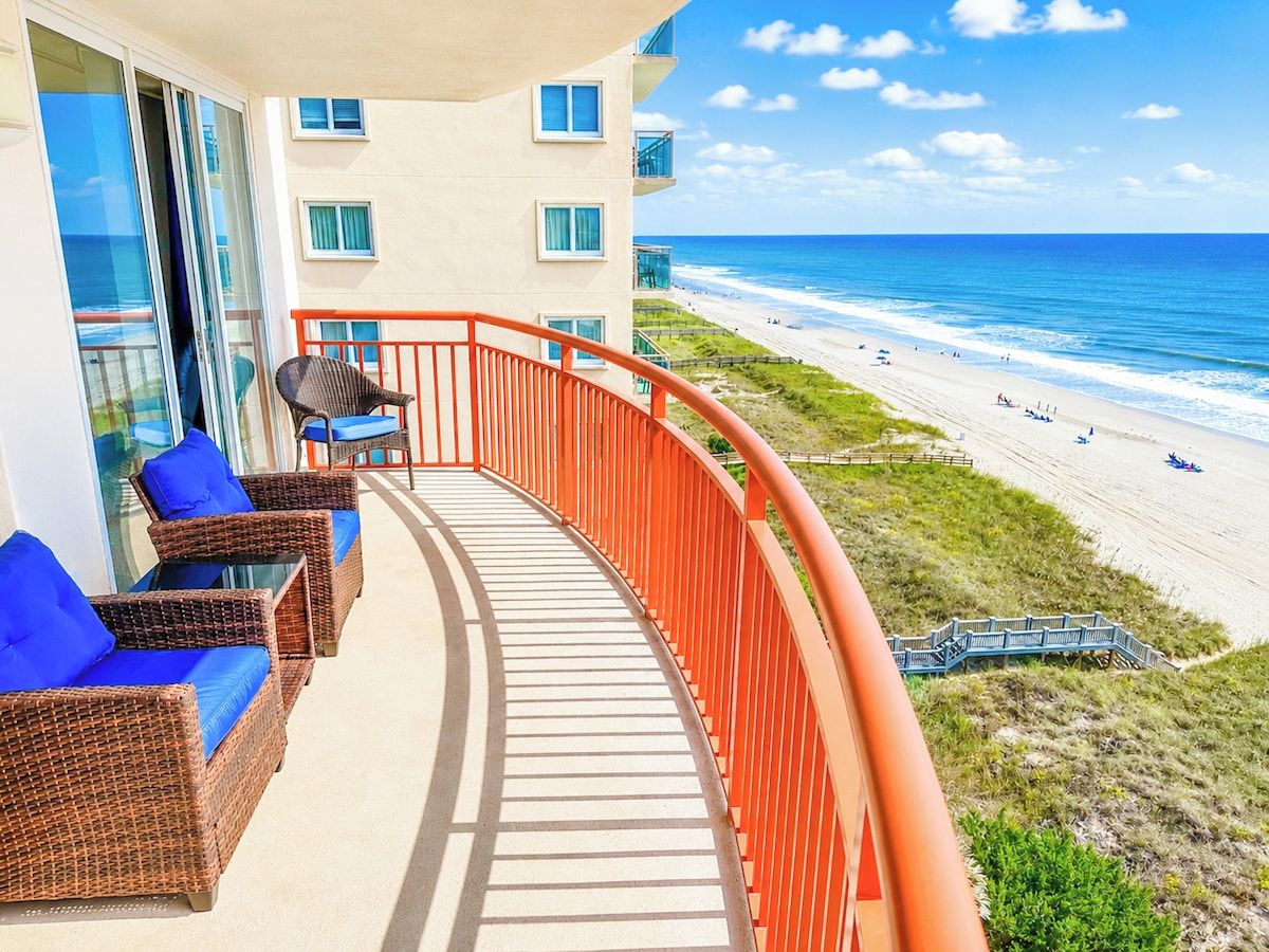 A balcony with wicker furniture and a view of the beach.