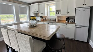 A modern kitchen with white cabinets, a central island with a vase of flowers, and a Galanz refrigerator. - River Front Property With Water View, Minutes To Brackley, & Screened In Dining (Oyster Bed)