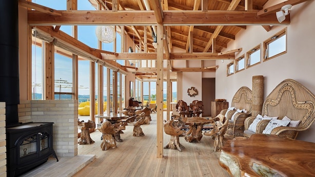 Una habitación amplia con techo alto, vigas de madera, ventanas grandes y chimenea.