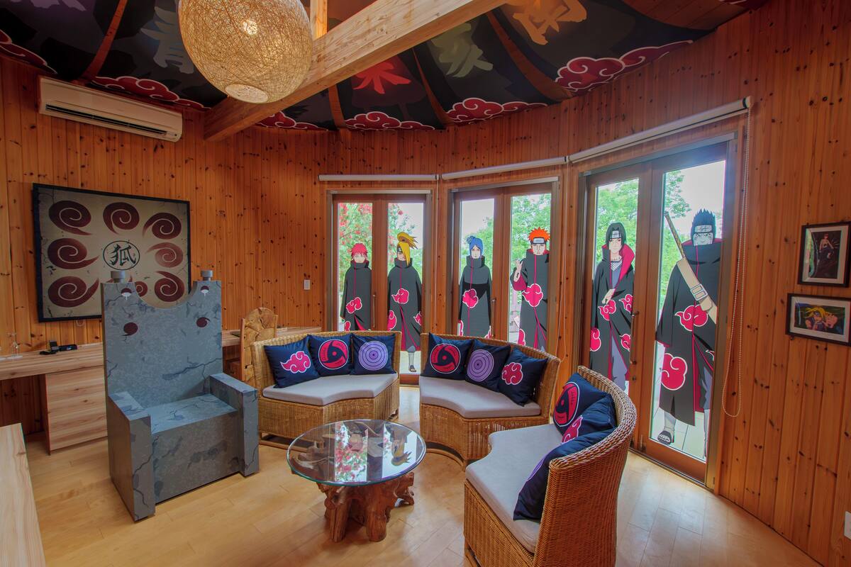 Un intérieur en bois, décoré dans le style traditionnel japonais, avec des tatamis, de basses tables et des portes coulissantes ornées de personnages d’anime.
