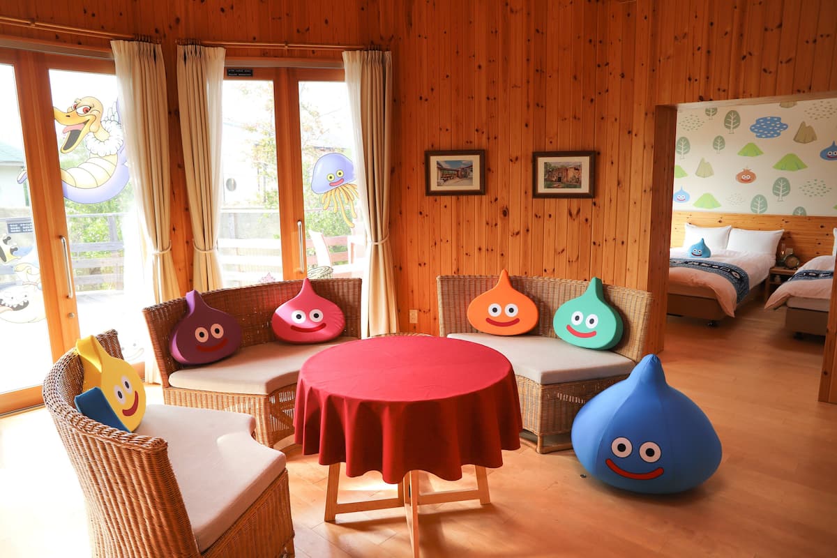 Une pièce avec une table ronde, des meubles en osier et des fauteuils colorés en forme de sac de haricots.