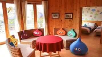 Ein Zimmer mit einem runden Tisch, Korbmöbeln und bunten Sitzsäcken.