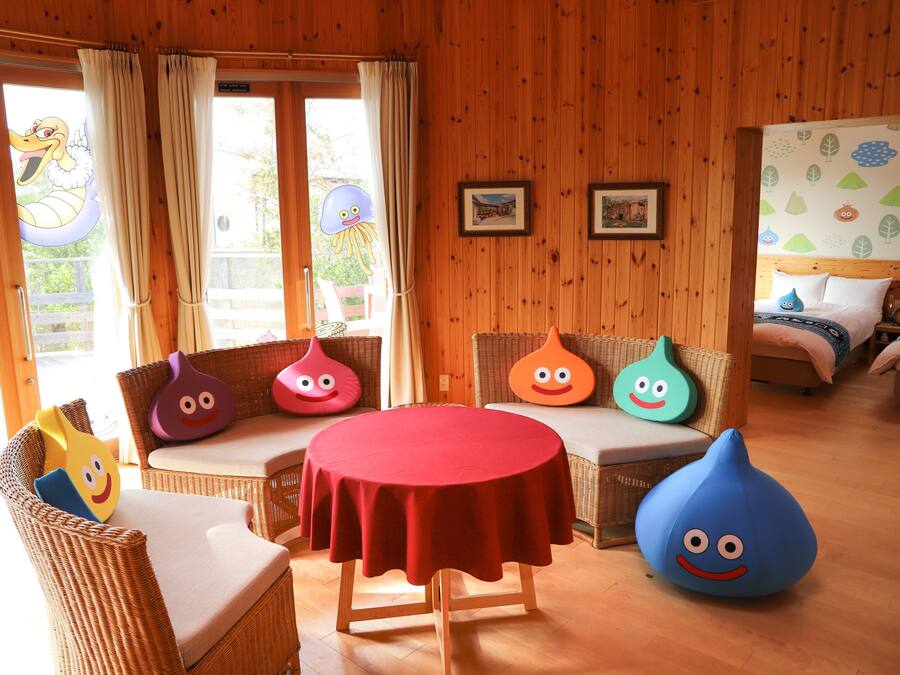 Ein Zimmer mit einem runden Tisch, Korbmöbeln und bunten Sitzsäcken.