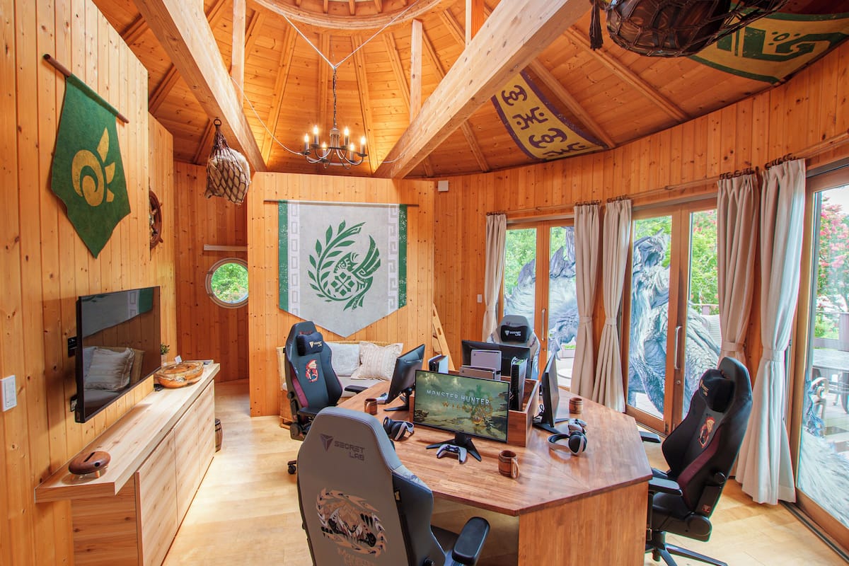 Une cabane en bois équipée d’un espace de jeu comprenant un grand écran, des fauteuils de jeu et un téléviseur.