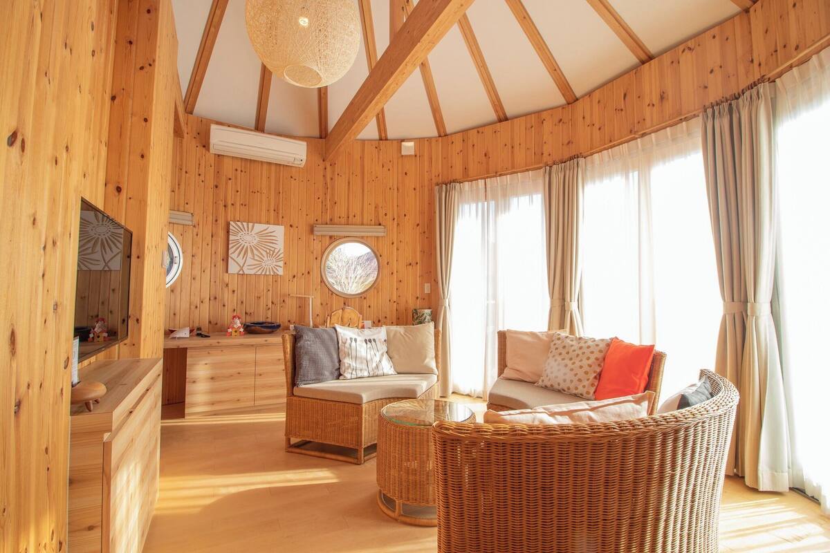 Un intérieur en bois avec un canapé, un fauteuil en osier et une petite table.