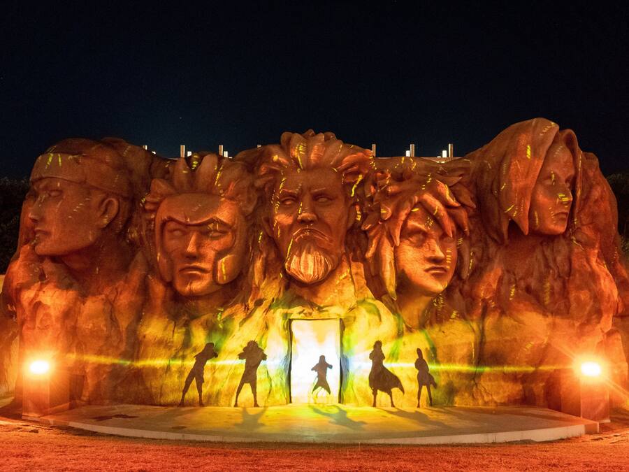 A large outdoor sculpture with multiple figures and a central doorway.