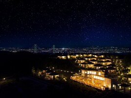 Un hotel con varias construcciones, vistas a un paisaje urbano y un puente al fondo.