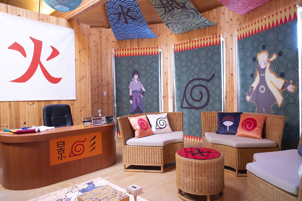 Une pièce comprenant un comptoir d'accueil, des meubles en osier et des éléments décoratifs, notamment un grand panneau mural et un papier peint à motifs.