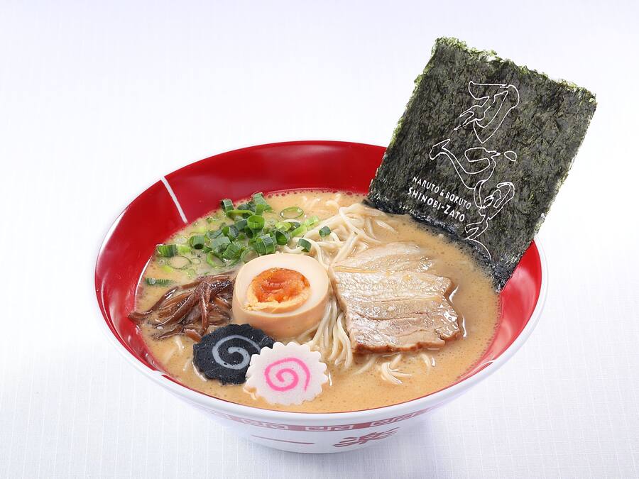 A bowl of ramen with various toppings including a soft-boiled egg, green onions, and seaweed.