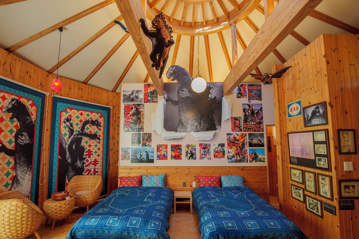 Une chambre avec deux lits, un plafond en bois et divers affiches et tableaux accrochés aux murs.