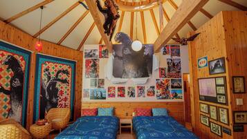 A room with two beds, a wooden ceiling, and various posters and pictures on the walls.