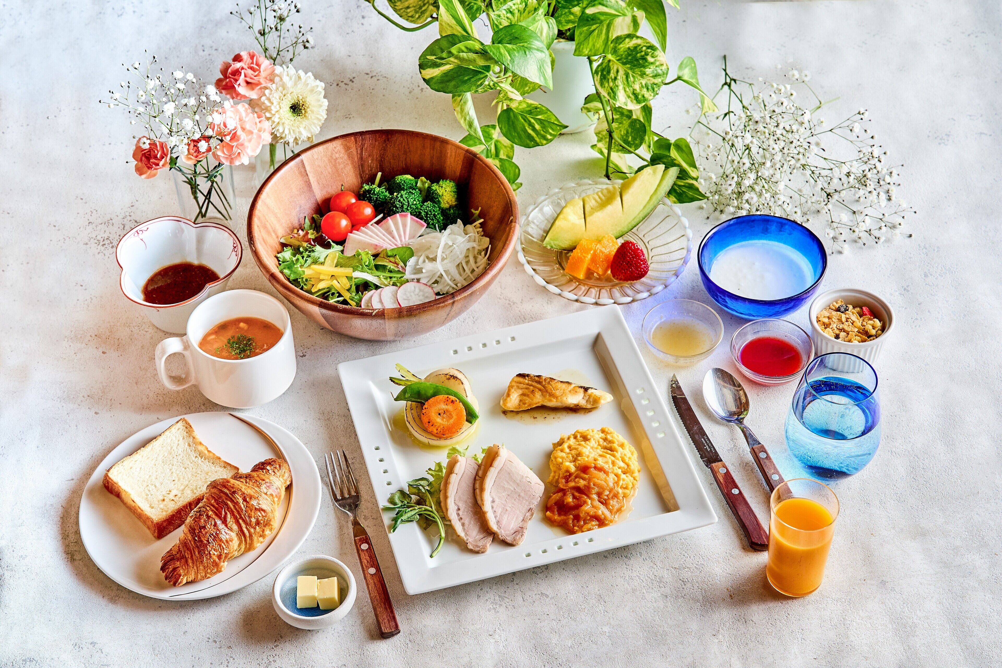 Desayuno con tostadas, un croissant, fruta, huevos y una taza de café.