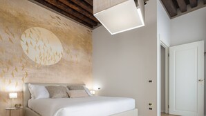 Ein Schlafzimmer mit einem großen Bett, Holzboden, einer Wand mit kreisförmigem Design und einer Deckenleuchte.