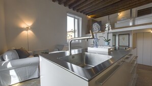 A modern kitchen with a built-in island, stainless steel appliances, and a wooden ceiling. - Zattere Design Loft R&R (Venecia)