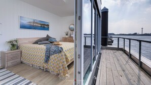 Un dormitorio con cama, mesita de noche, cómoda y ventana, con vista al mar.