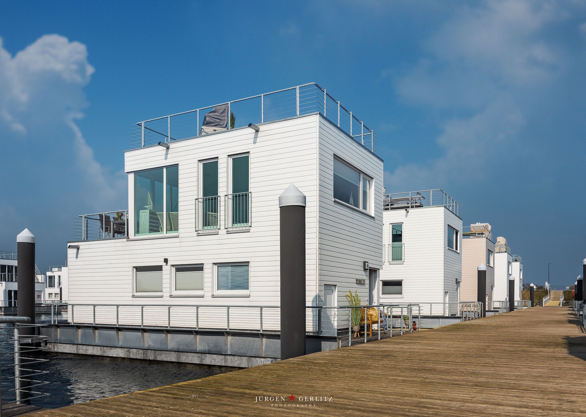 A waterfront property with a modern design, featuring a dock and a wooden walkway.