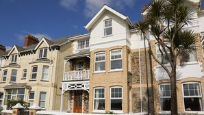 A row of terraced houses with a central balcony, stone walls, and a palm tree. - Foreshore - sleeps 16 guests  in 9 bedrooms (Bude)