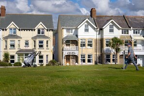 A row of terraced houses with a grassy front yard and a person walking.