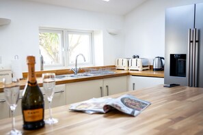 Una cocina moderna con encimera de madera, electrodomésticos de acero inoxidable y ventana que deja entrar luz natural.