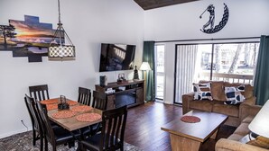 Una sala de estar moderna con comedor, televisor y sofá.