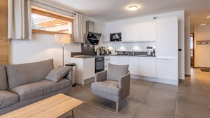 A modern apartment with a living area, kitchenette, and a small dining space.