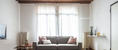A living room with a sofa, a coffee table, a TV, and a radiator.